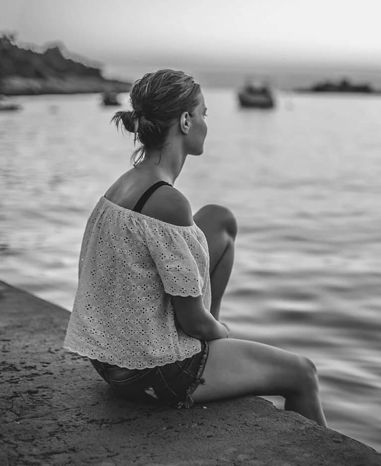 Traveler sitting on a seawall looking out over the water